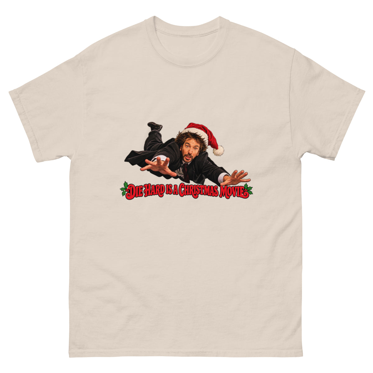 Die Hard Is a Christmas Movie T-skjorte med John McClane inspirert av Bruce Willis, iført nisselue og svart dress, over rød juletekst med kristtorn.